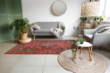 Interior of cozy living room with sofa, houseplants and vintage carpet