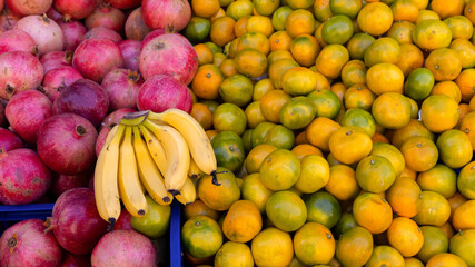 lemons, bananas, apples, tangerines and pear on a table of wooden planks.