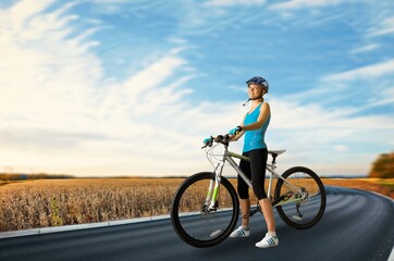 Happy woman dressed in cycling clothes, helmet and sunglasses riding a bicycle