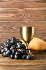 Cup of wine with grapes and bread on wooden background