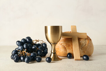 Cup of wine with bread, grapes and cross on light background