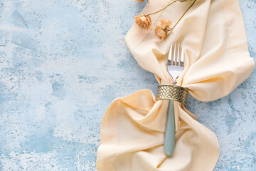 Fork with napkin and flowers on blue background