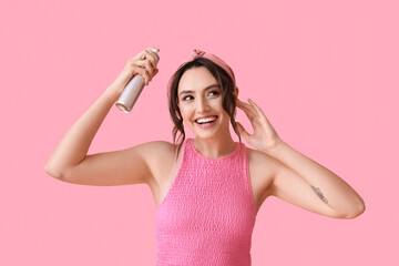 Pretty young woman with hair spray on pink background