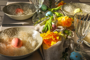 Fototapeta na wymiar Beautiful table setting with Easter eggs and flowers, closeup
