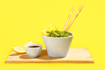 Bowl with healthy seaweed salad on yellow background
