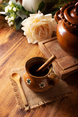 Authentic homemade mexican coffee (cafe de olla) served in traditional clay mug (Jarrito de barro) on rustic wooden table.