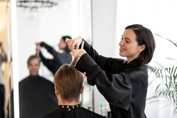 Dark-haired hairdresser working on a stylish haircut