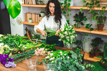 Attractive young woman florist is working in a flower shop.