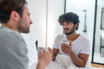 Cute man drinking coffee with his partner in the bedroom