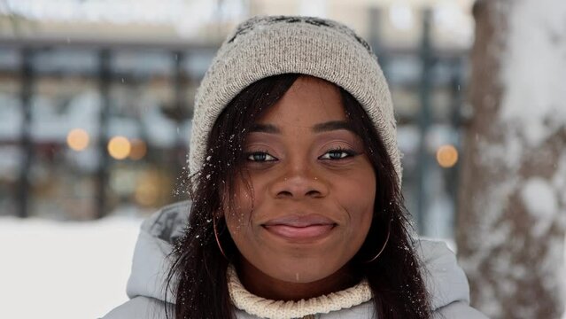 Young black woman stands in winter forest and smiles to the camera