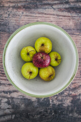 group of green apples with one red apple in the middle, healthy food or metaphor of standing out from the crowd