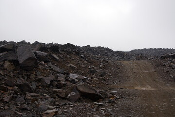 Old abandoned huge coal pit. Nature pollution. Ruins and stones. Ruins and huge mountains of dirty rock. 