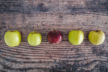 group of green apples with one red apple in the middle, healthy food or metaphor of standing out from the crowd