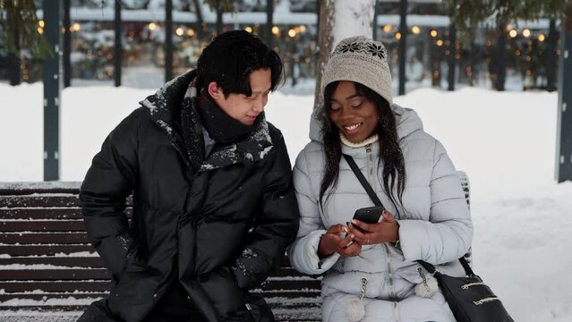 Young black woman showing memes on her phone to her asian boyfriend