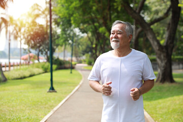 Happy and smiling asian senior man doing exercise and jogging or walking with relaxation for healthy in park outdoor after retirement during summer time. Health care elderly outdoor lifestyle concept.