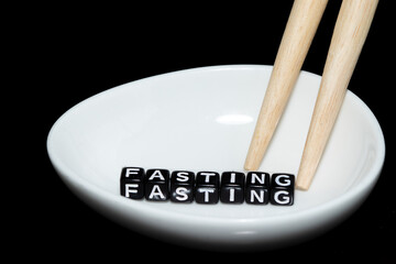 Mote alphabet blocks arranged into "Fasting" ceramic and chopsticks.