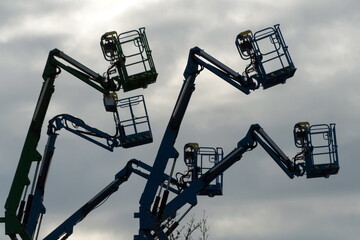 Silhouettes of boom  lifts against dusk sky
