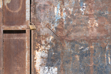 Padlock on old and rusty metal door.  