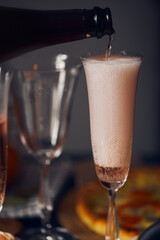 Champagne is poured from a bottle into a glass of retro style. Vertical photo.