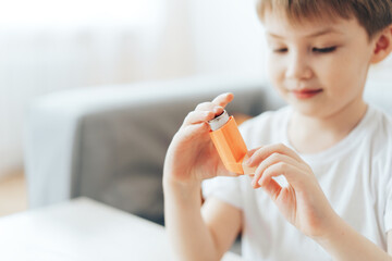 Little boy holding asthma inhaler close up. - obrazy, fototapety, plakaty