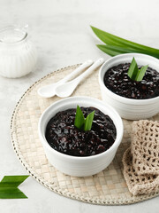 Bubur Ketan Hitam, Indonesian dessert. Black glutinous rice porridge with coconut milk, sugar and pandan leaf. Blurred background and selective focus.