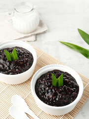 Bubur Ketan Hitam, Indonesian dessert. Black glutinous rice porridge with coconut milk, sugar and pandan leaf. Blurred background and selective focus.