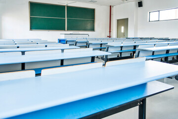 Bright university classroom with blue desks and chalkboard