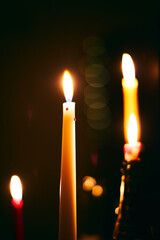 Many candles burn in the dark. The concept of waiting for a holiday and comfort in winter. Vertical photo.