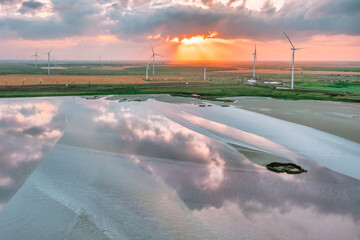 Amazing aerial view of a wind turbine near a pink lake at sunset, beautiful landscape, juicy multi-colored paints