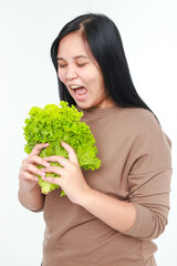 Fat Asian woman eating lettuce to lose weight. Concept of eating healthy, clean, safe. White background.