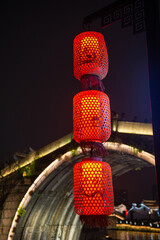 Strings of red lanterns hanging by the stone arch bridge in the ancient town during Chinese New Year