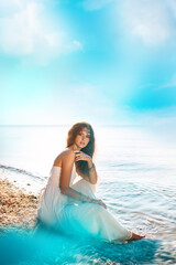 Fototapeta na wymiar beautiful young stylish woman sitting on sand on the beach