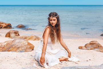 beautiful young stylish woman sitting on sand on the beach