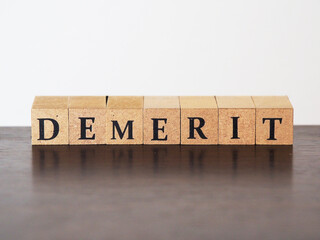 デメリット(demerit)と書かれた木のブロックのタグ