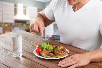 attractive handsome male eating health food salad and chicken at home. Active young man sit on table, healthy foods and clean water for breakfast to diet for health care