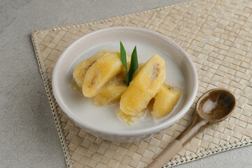 Kolak, Kolak Pisang is Indonesian traditional dessert, very popular during Ramadhan, made from banana with coconut milk, sugar and pandanus leaves. Served in white bowl on grey background, copy space.