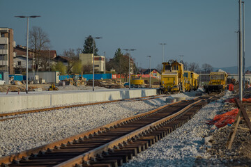 Fototapeta na wymiar Train station of Grosuplje under renovation. New fresh tracks laid next to the passenger platform, visible rail plough, tamper and some waggons.