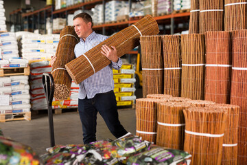 Portrait of man buying braided wooden fence in hypermarket