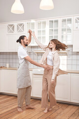 Beautiful young couple is dancing and smiling together in kitchen