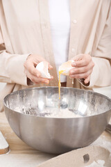 Female hands break an egg in the kitchen into a bowl for cooking.