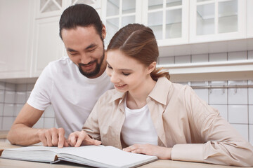 Couple in love in the kitchen reading a recipe book