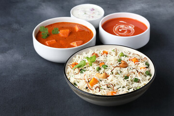 Indian food Vegetable biryani with Paneer butter masala, tomato soup and Curd raita