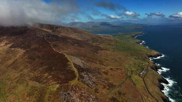 Ventry, Kerry, Ireland, March 2022. Drone pushes towards the rugged landscape from the southwest by Dingle Bay along the Wild Atlantic Way with Ballymacdoyle and Dooties in the distance.