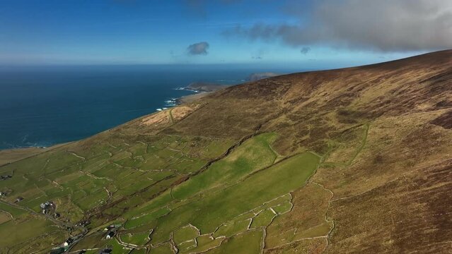 Ventry, Kerry, Ireland, March 2022. Drone descends above ancient rugged farmland towards Ventry from the north with the Blasket Islands and North Atlantic Ocean in the distance.