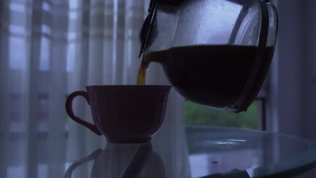 Reflective image of a hand serving coffee in the morning, with dark and sad atmosphere