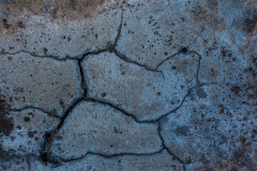 Texture of the dried earth. Dark gray background with cracks and hollows. Drought and lack of moisture in the soil. The consequences of abnormal heat. Environmental disaster. Global warming.