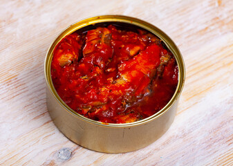 Canned seafood - sprat in tomato sauce on wooden surface