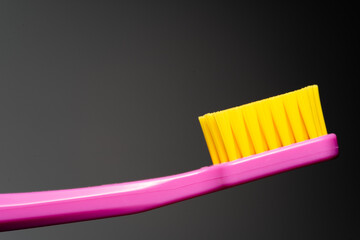 toothbrush with pink handle yellow brush head. Toothbrush closeup on white background.