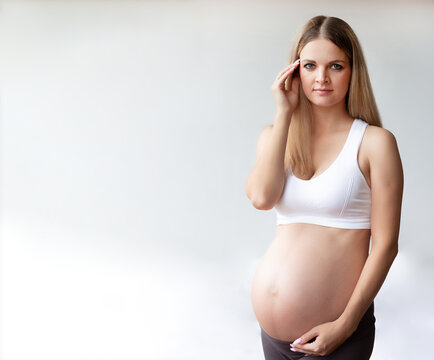 Portrait. Pretty pregnant blonde woman with an open belly. On a light background. Looks into the camera. High quality photo. copyspace. 