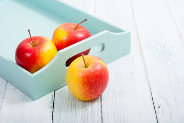 apples at blue tray, white wood table